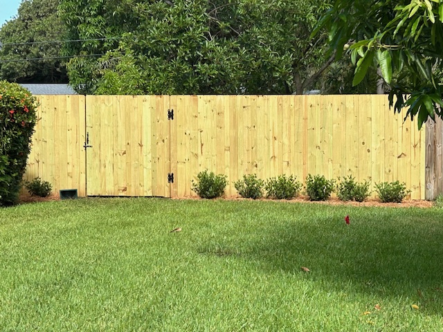 Board-on-board wood privacy fence installation creating a natural solid visual barrier